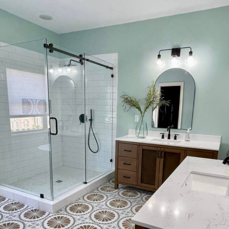 Spa-inspired bathroom remodel with freestanding tub, walk-in glass shower, patterned tile floor, and wood vanity