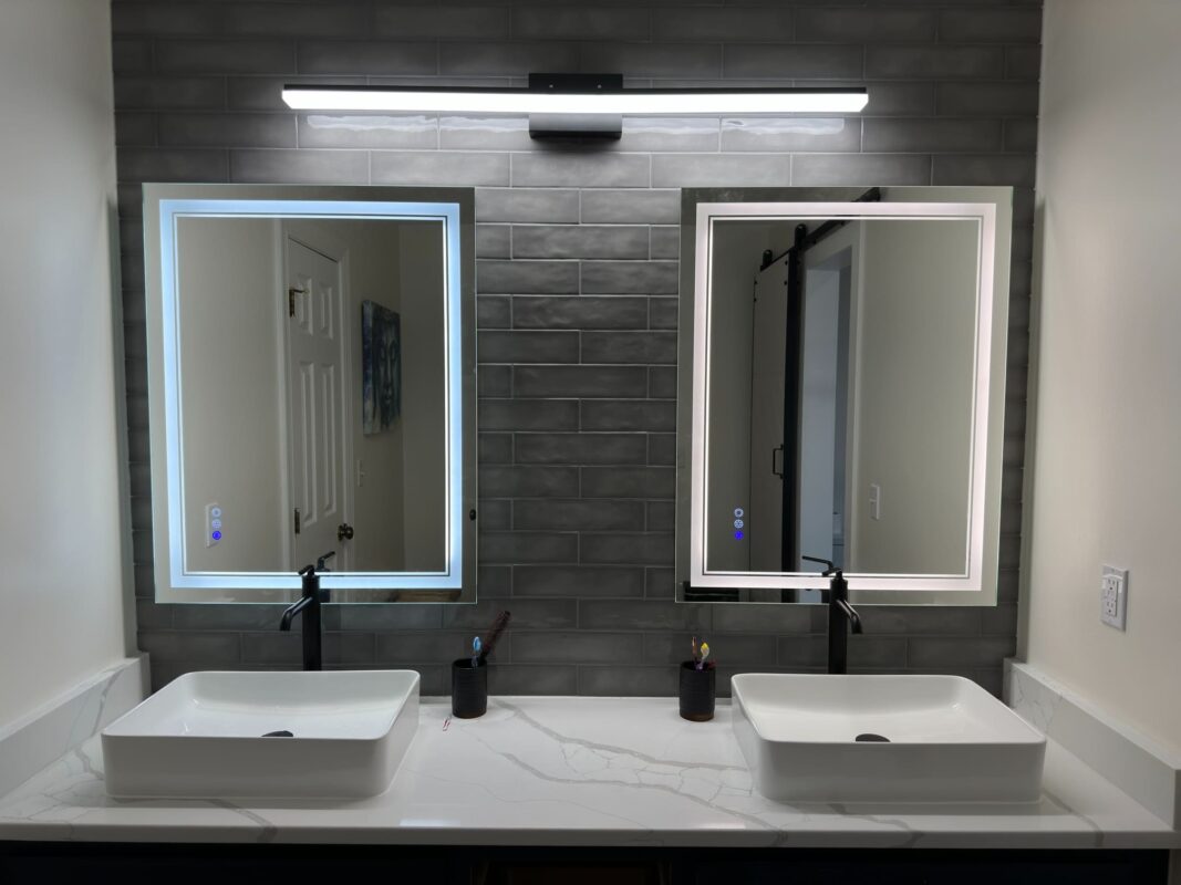 Modern bathroom with frameless glass shower, dual-sink vanity, and LED mirrors