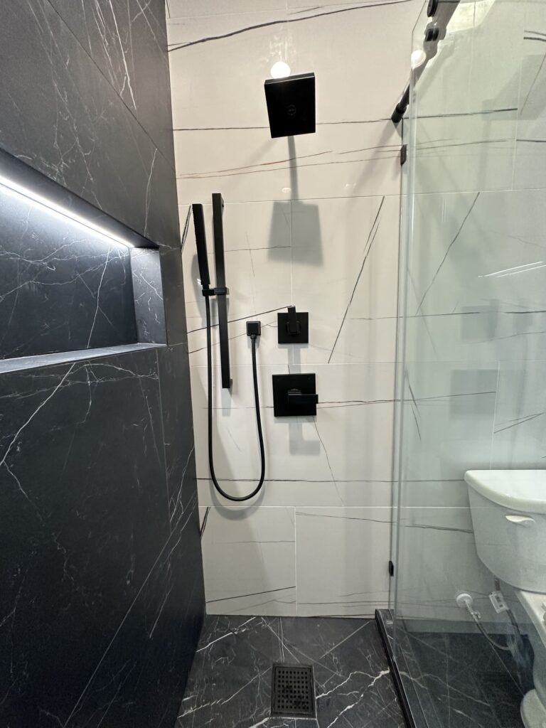 Modern bathroom remodel with contrasting tile walls, black hardware, and updated vanity
