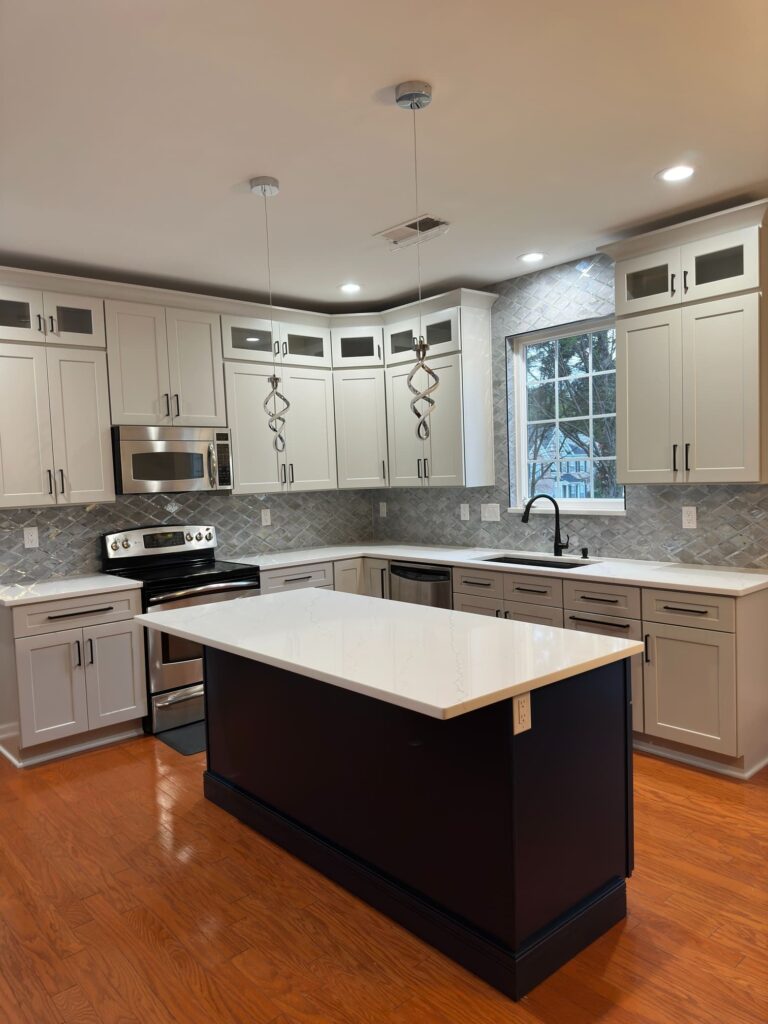 Two-tone kitchen remodel with large island, textured backsplash, and modern pendant lighting