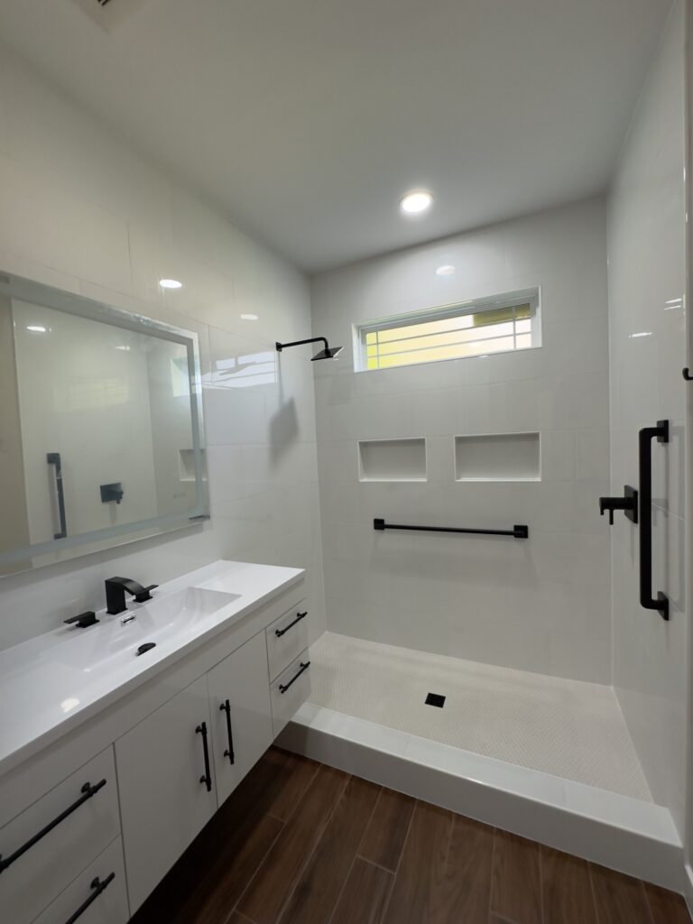 Minimal bathroom with walk-in shower, white vanity, and tall built-in storage cabinets