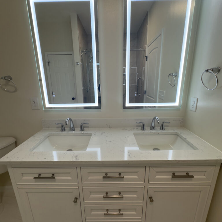 Bright bathroom remodel with walk-in glass shower, double vanity, illuminated mirrors, and neutral tile