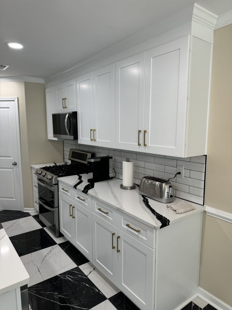 Bold kitchen remodel with white cabinetry, large island, and black-and-white tile flooring