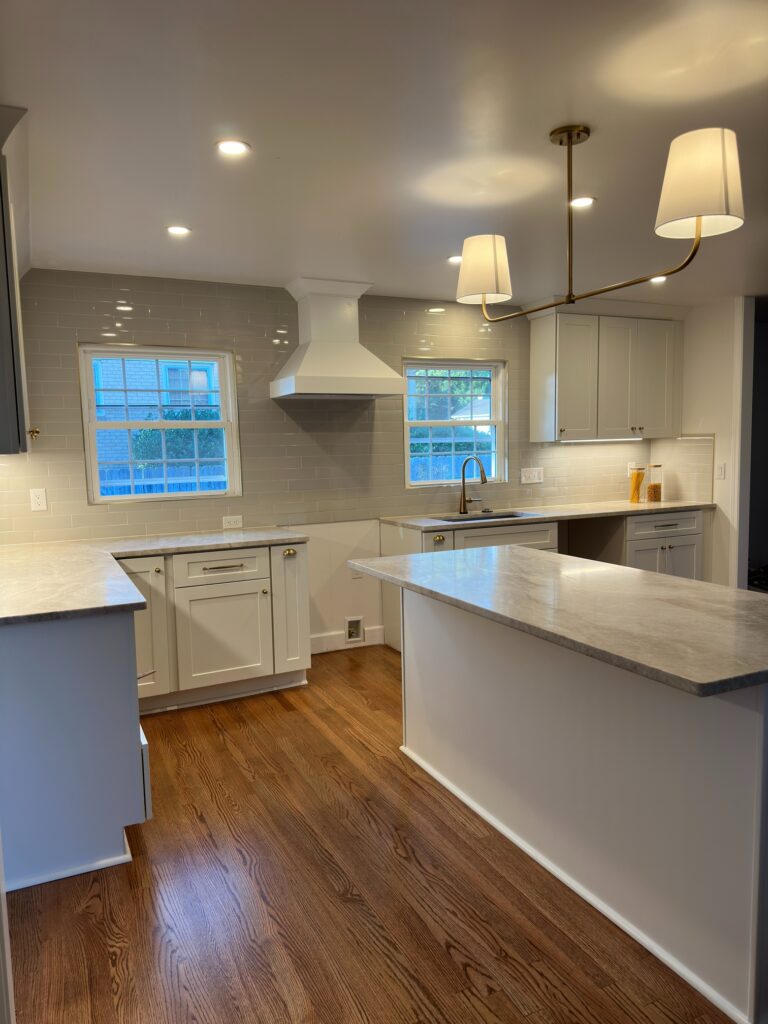 Classic kitchen remodel with white shaker cabinetry, large island, and wood flooring