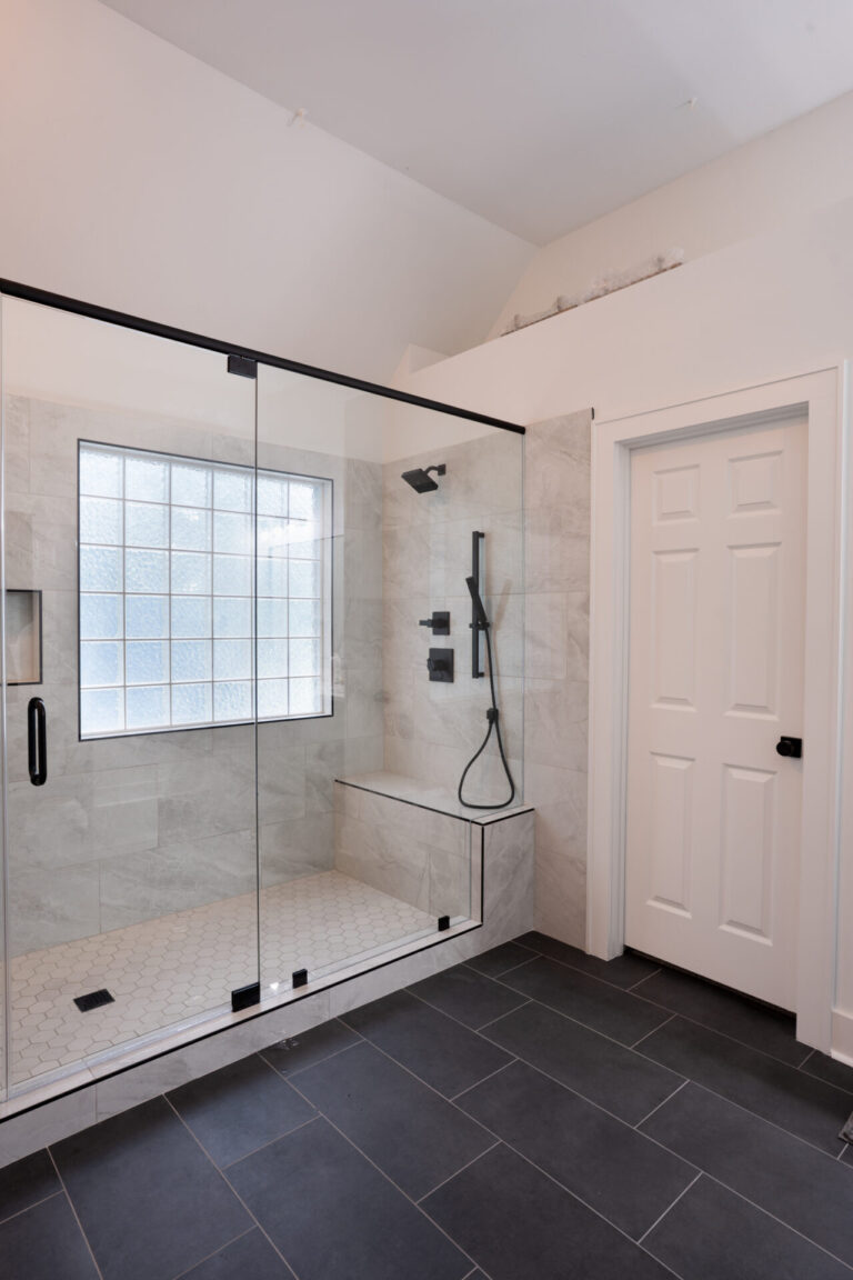 Wet room bathroom with walk-in glass shower, freestanding tub, and marble-look tile