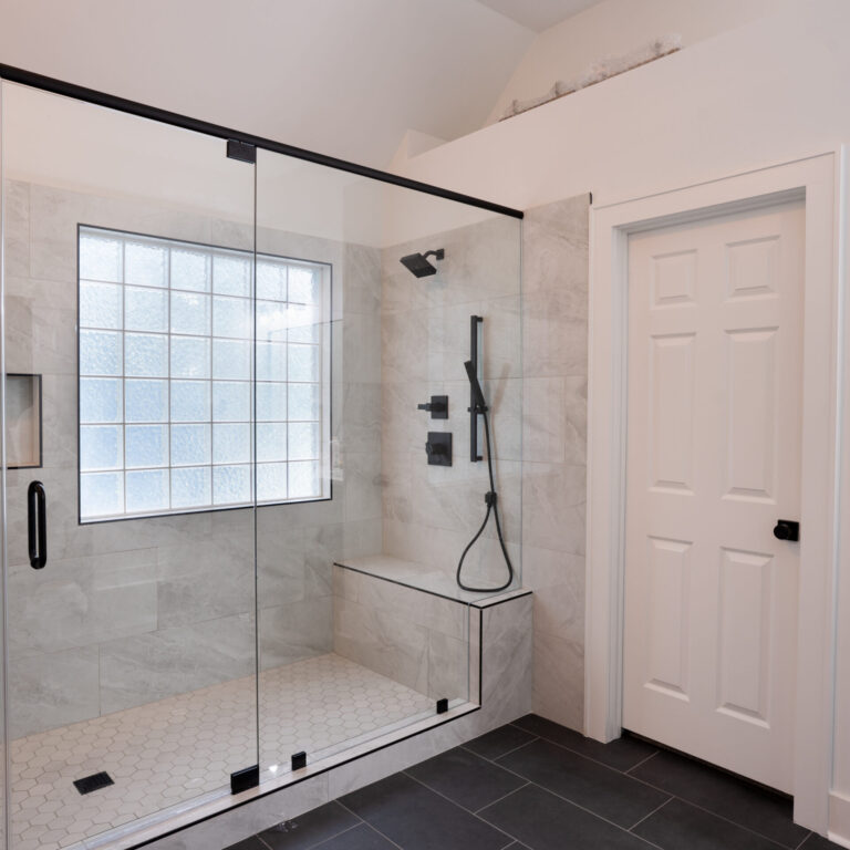 Modern wet room bathroom with walk-in glass shower, freestanding tub, and marble-look tile