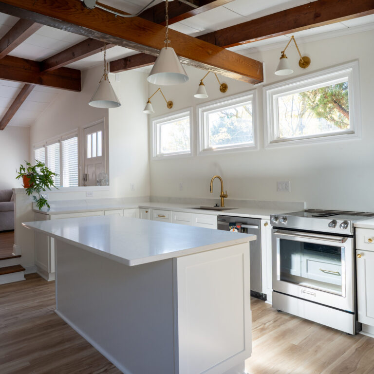 Bright kitchen remodel with white cabinetry, large island, and exposed wood ceiling beams