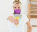 Portrait of a young woman holding paint brush in front of her face at the new house